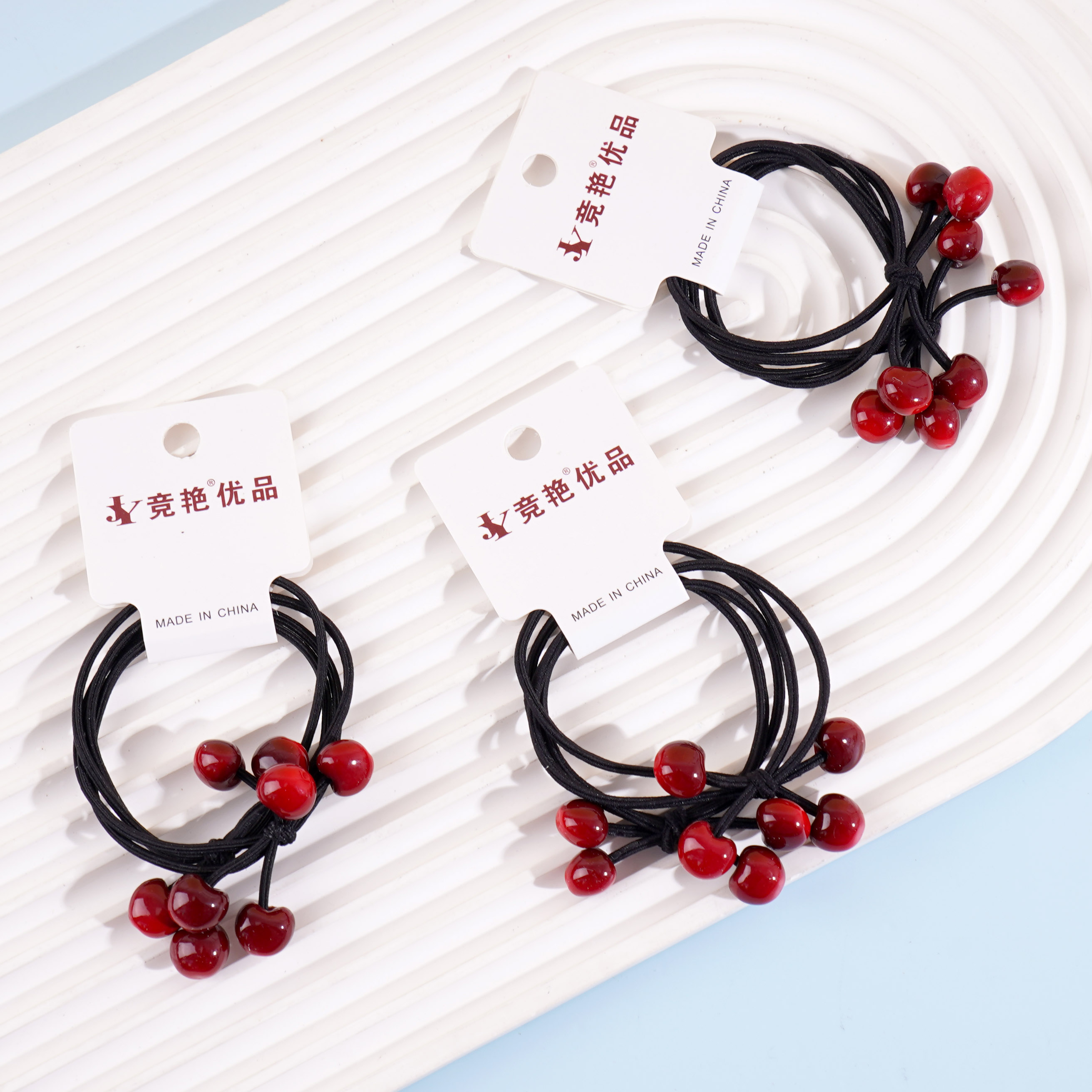 2 red cherry-shaped rubber bands with a string loop at each end