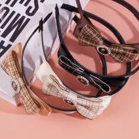 Une pince à cheveux avec un nœud à carreaux, une rose et un fermoir en diamant noir.