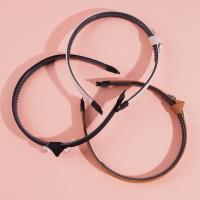 A dark-colored double-diamond headband buckle with a knotted design