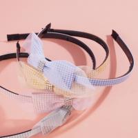 A children's headband with a bow made from checkered gauze and a hair clip