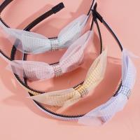 A children's headband with a bow made from checkered gauze and a hair clip