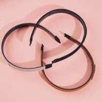 Dark-colored headband with a logo on it and a buckle for fastening the hair