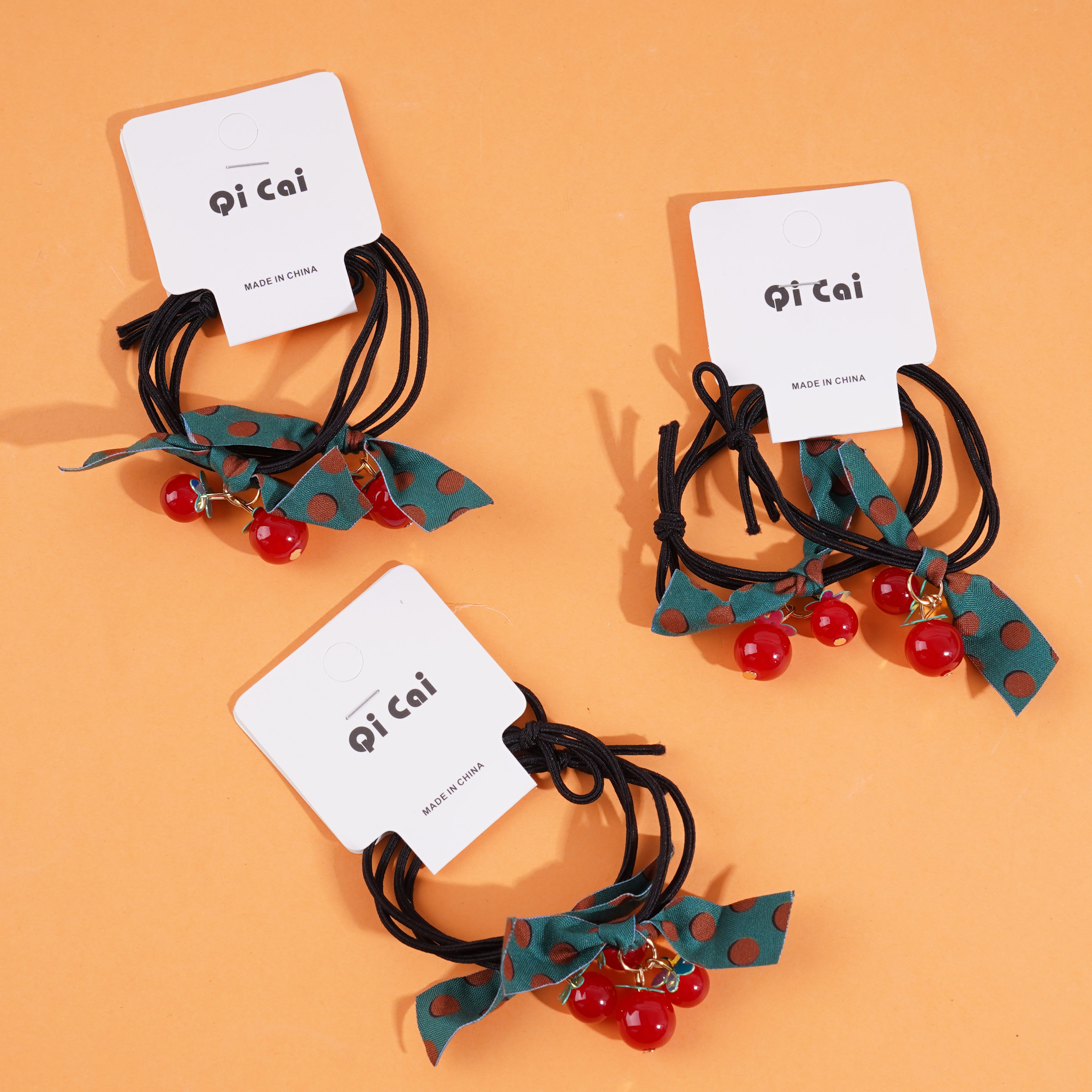 2 red beads, green ribbon headbands, and rubber bands