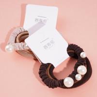 Une élastique pour cheveux composée de 3 cordes de couleur café et de 4 perles.