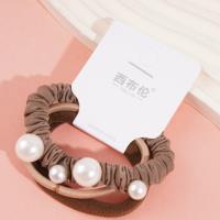 Une élastique pour cheveux composée de 3 cordes de couleur café et de 4 perles.