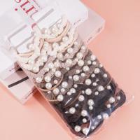 Une élastique pour cheveux composée de 3 cordes de couleur café et de 4 perles.